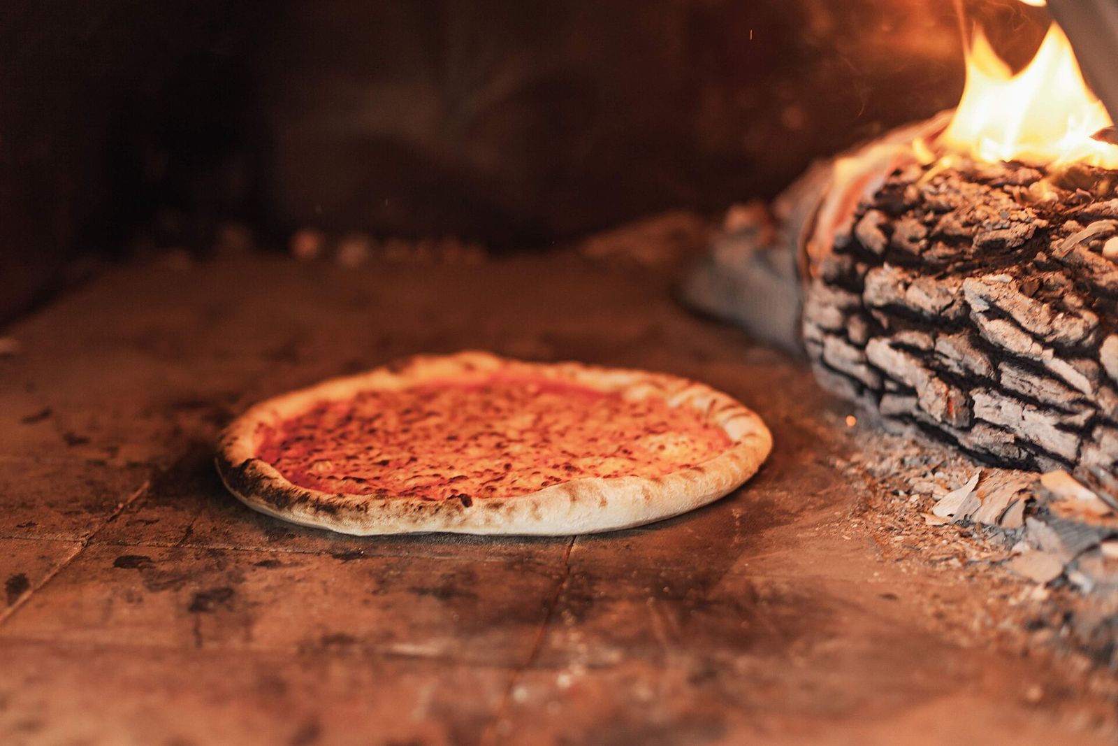 Pizza horneándose junto al fuego del horno a leña